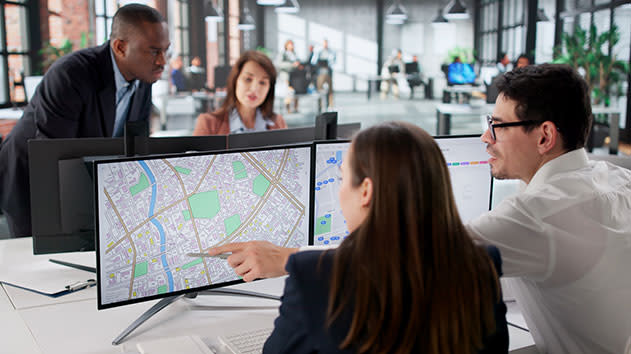Group of office workers looking through cadastral maps on a computer for surveying 