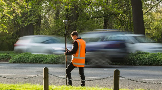 Surveyor in a roadway taking measurements using a trimble antenna