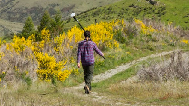 Surveyor holding a trimble antenna walking through a field