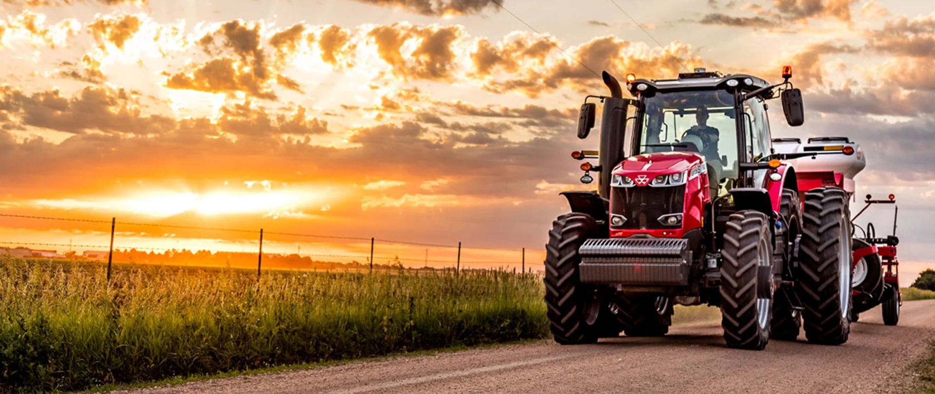 Tractor towing equipment down a dirt road