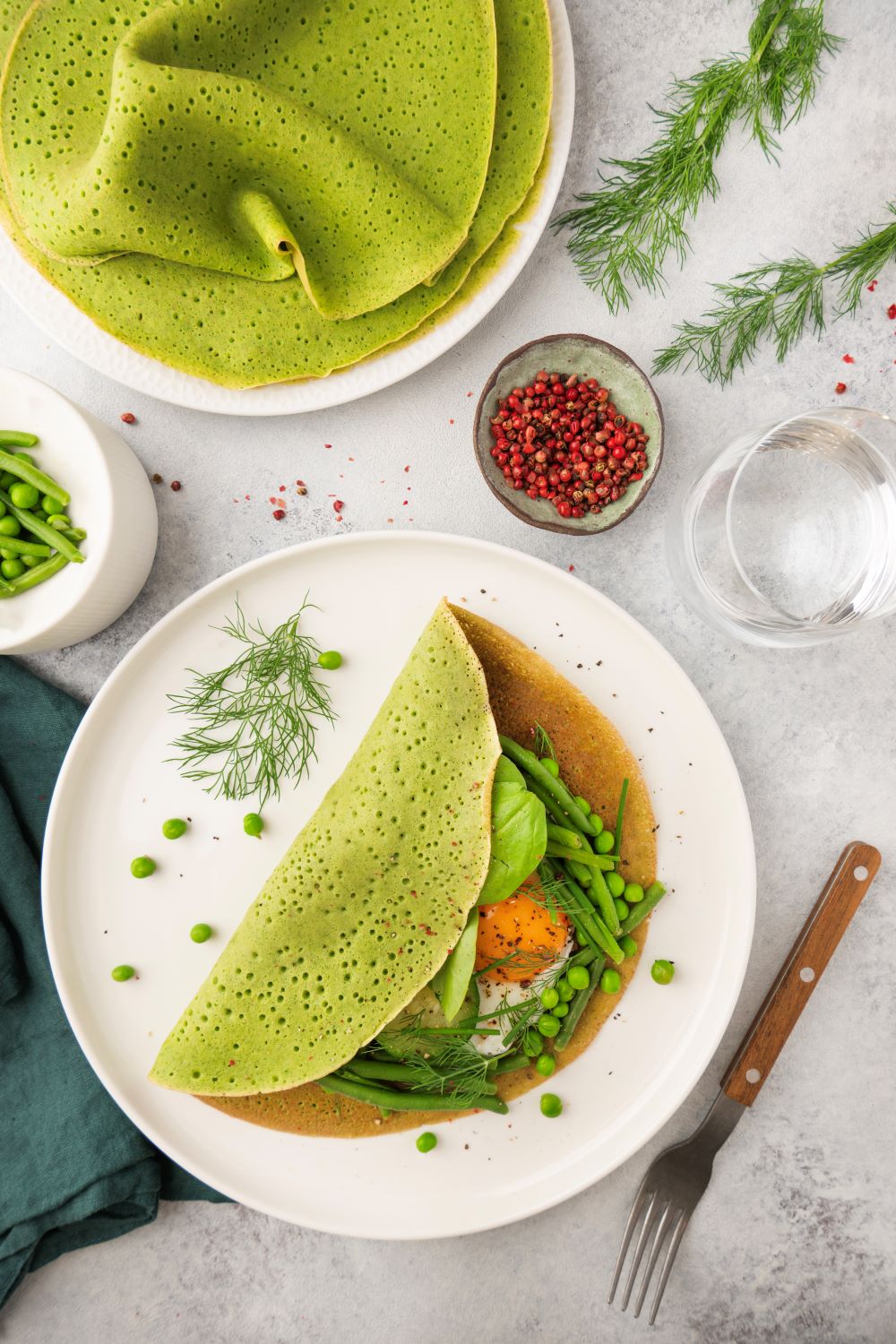 Crêpes salées aux épinards et lait de chèvre, garnies de légumes verts et d’un oeuf au plat