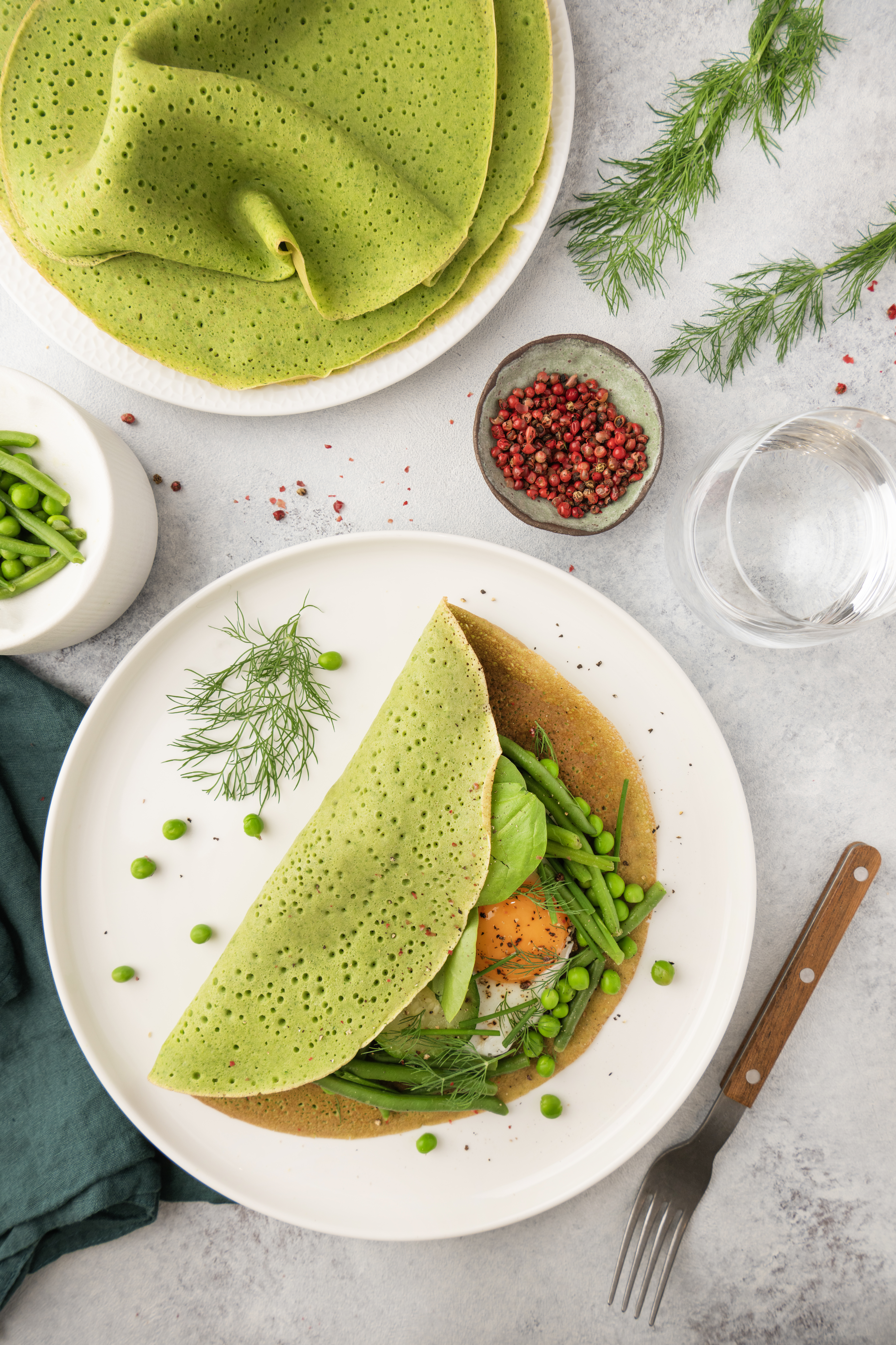 Crêpes salées aux épinards et lait de chèvre, garnies de légumes verts et d’un oeuf au plat