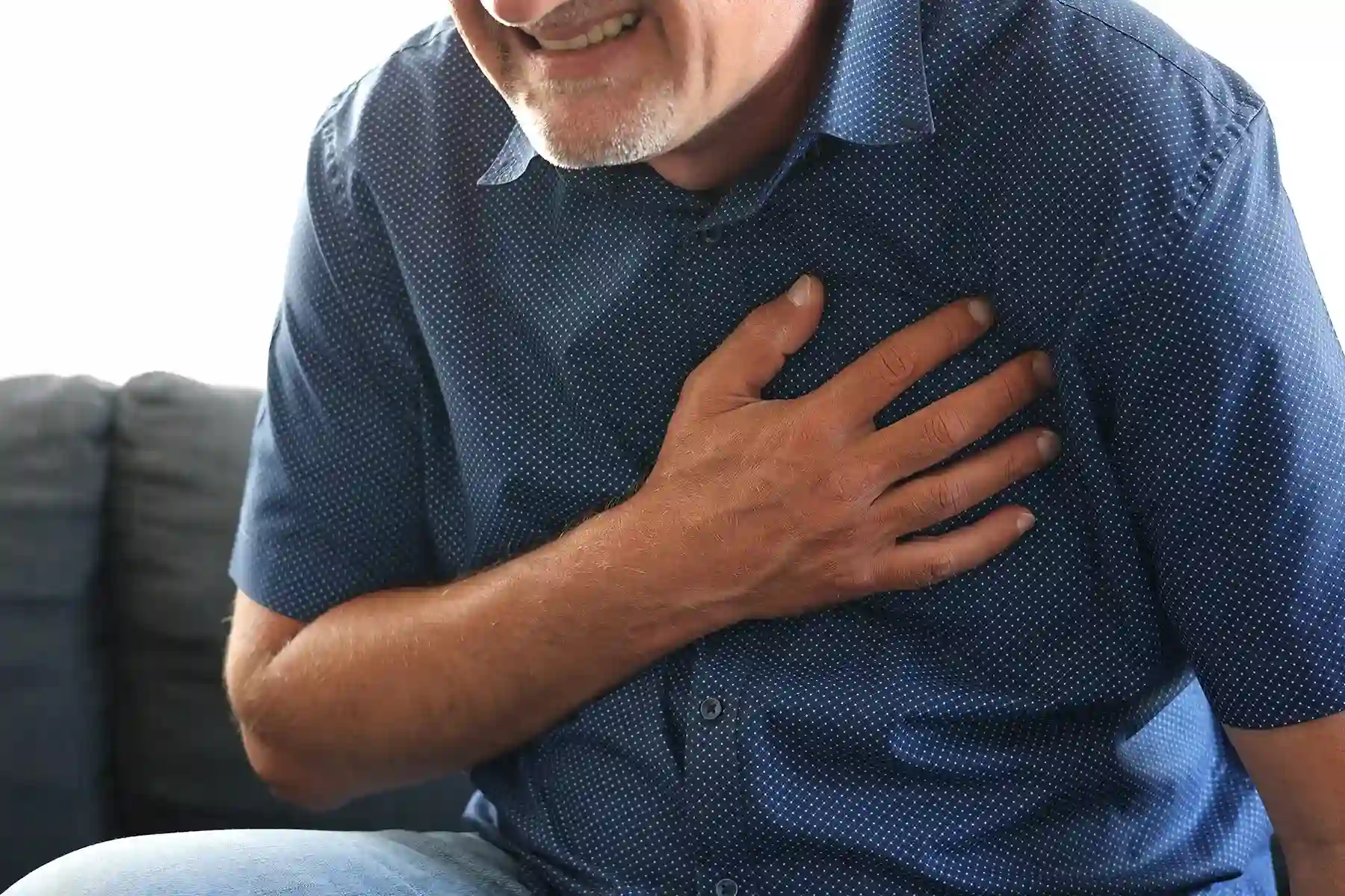 Man wincing as he holds his hand to his heart.