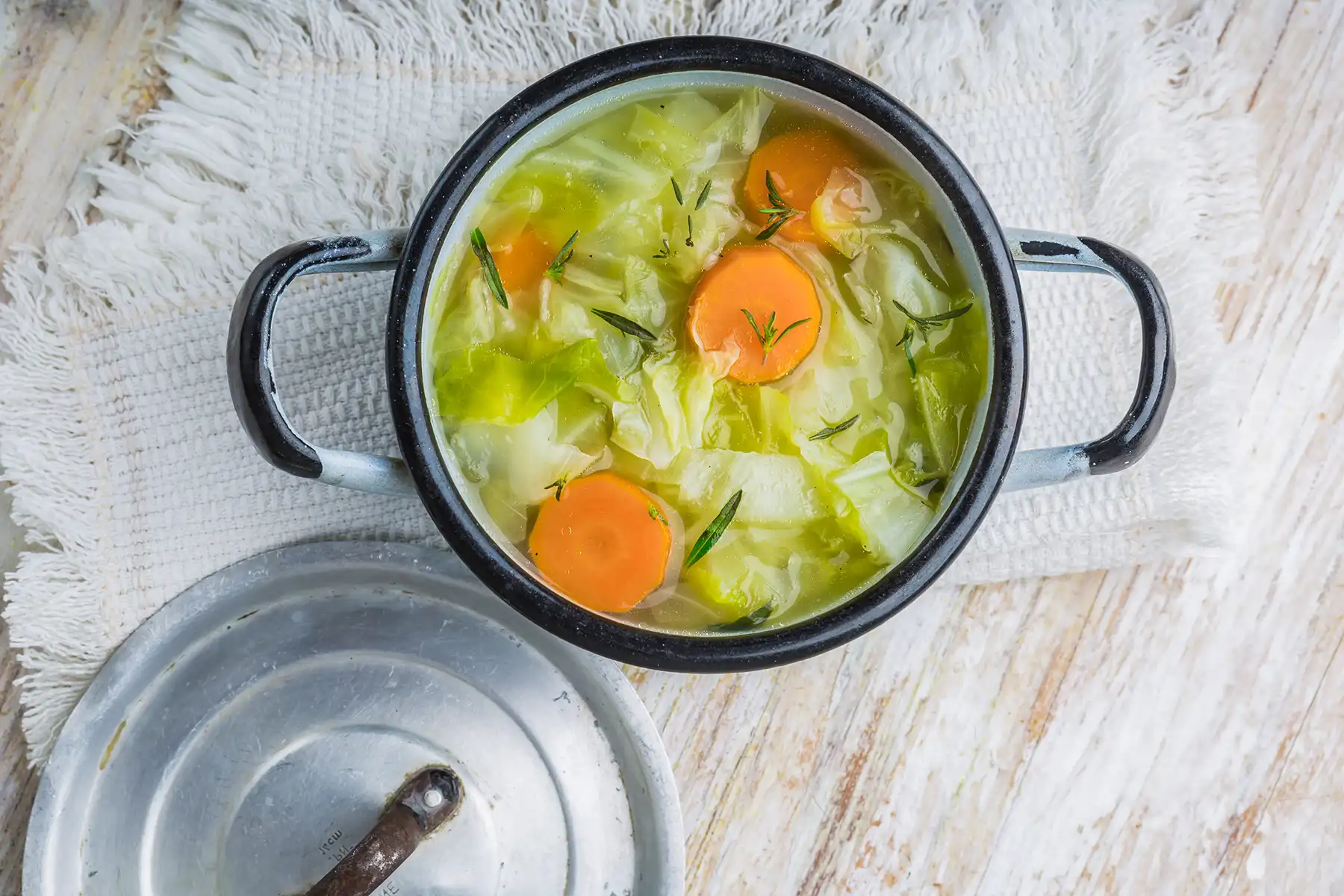 Cabbage soup with herbs and carrots in a dutch oven.