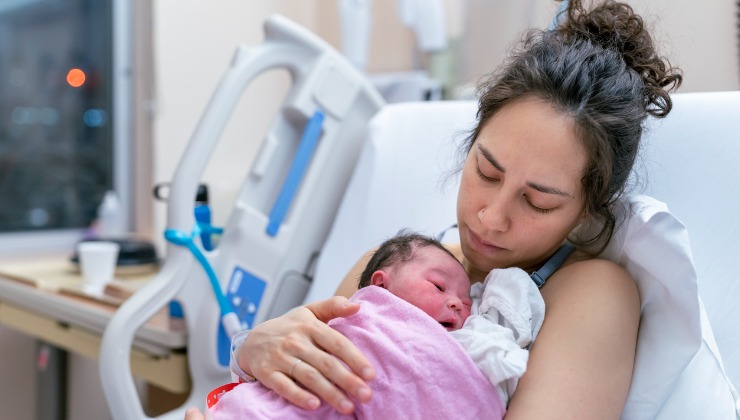 Woman holding her newborn baby in hospital bed.