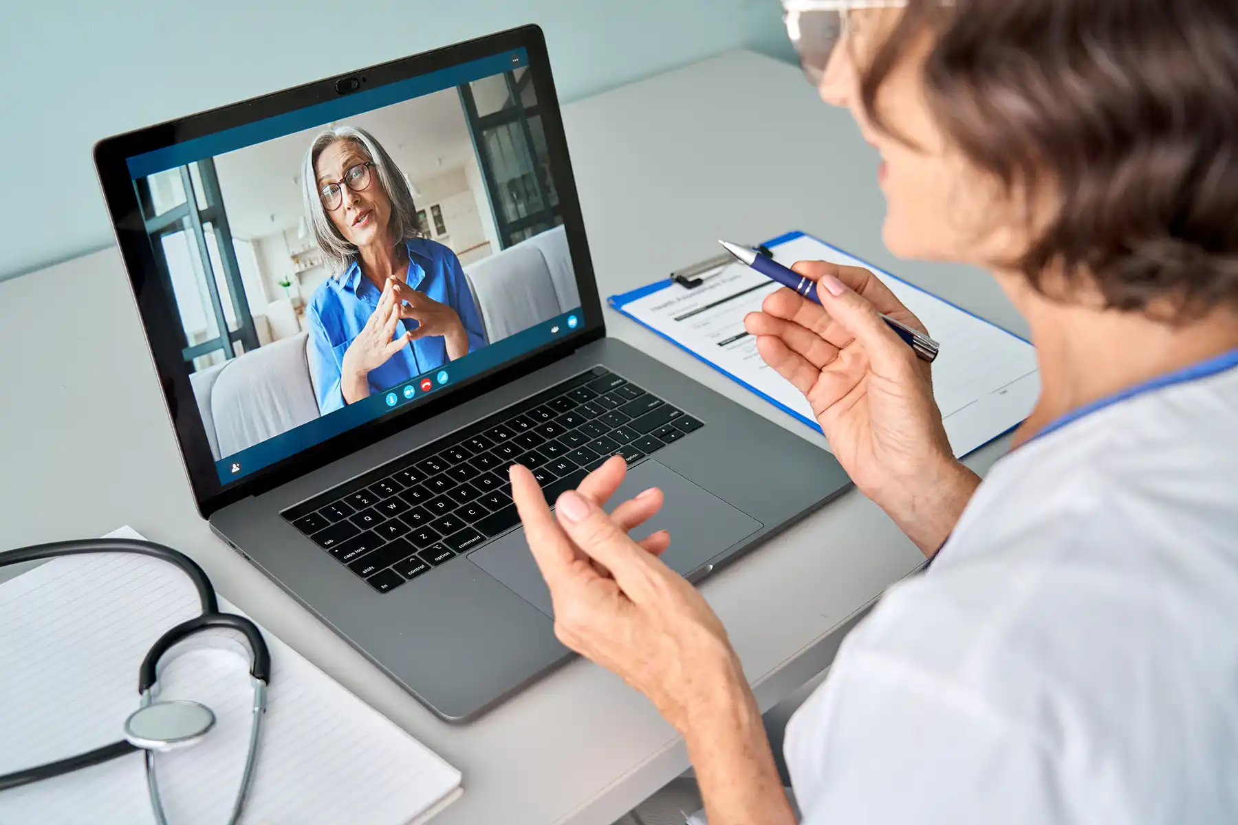 A doctor takes notes during her virtual call with a patient.
