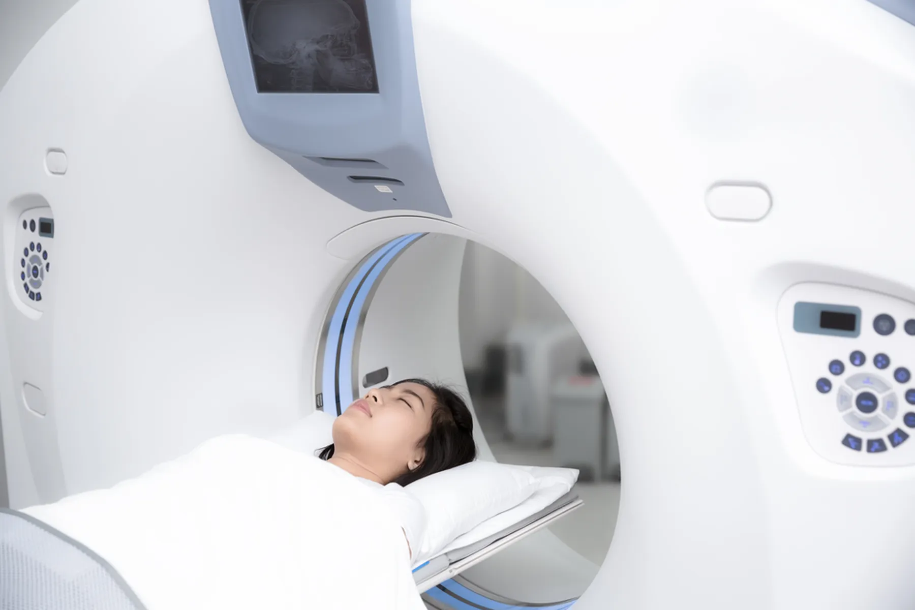 A woman's eyes are closed as she is moved into an MRI scan.