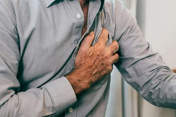 Older man gripping his chest, likely feeling pain.