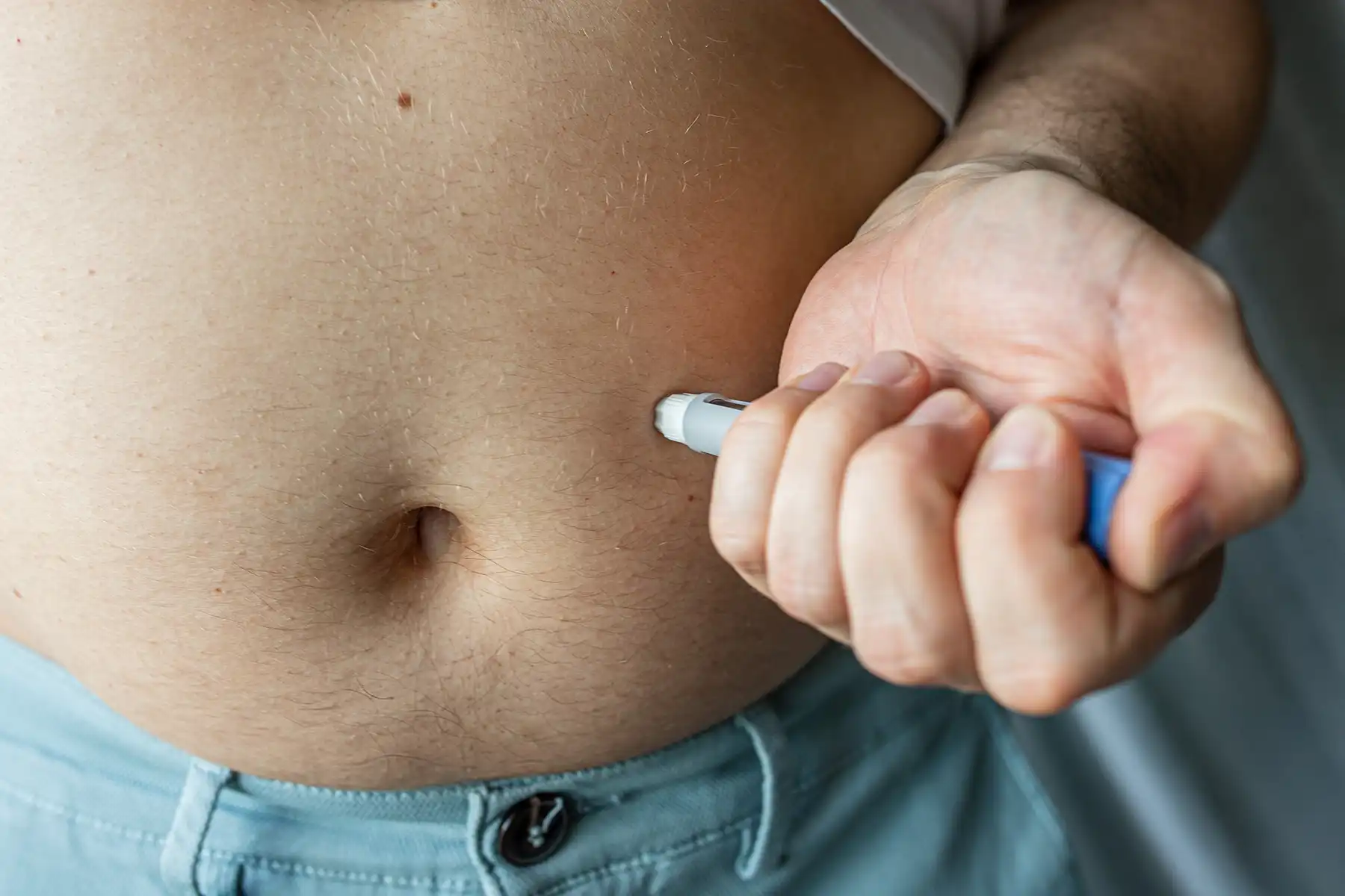 A man injecting his semaglutide into his stomach.