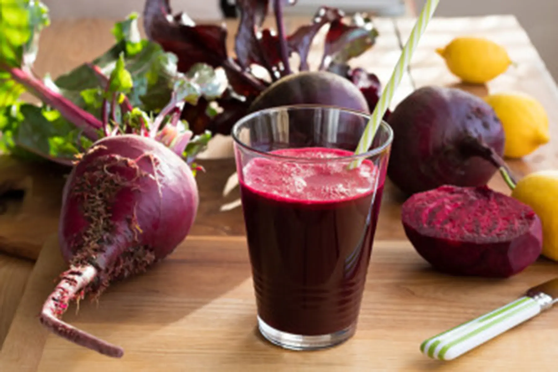 A cup of beetroot juice with beets around it.