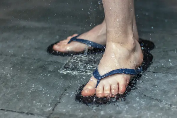 A person wears flip flops while showering.