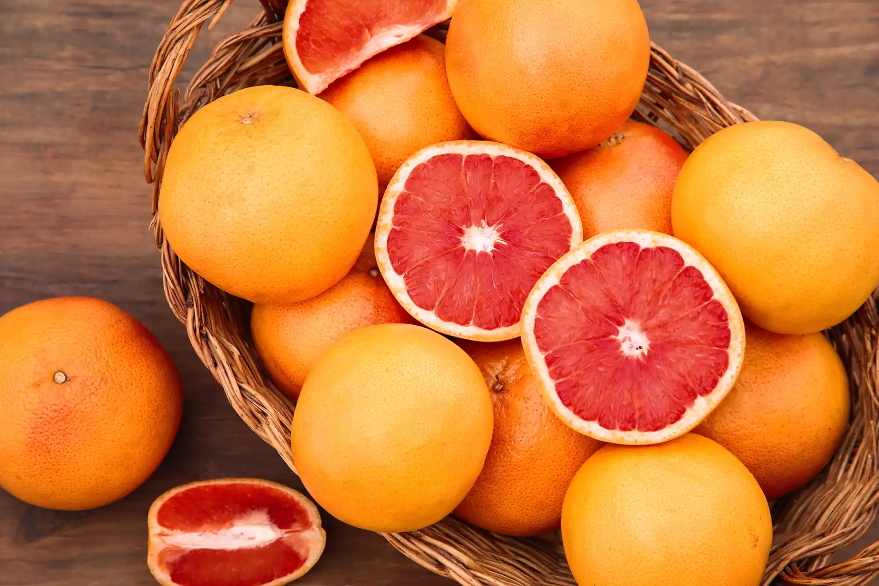 Various whole and halved grapefruits in a basket.