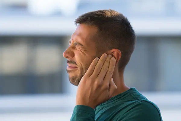 A man holds his ear in pain.
