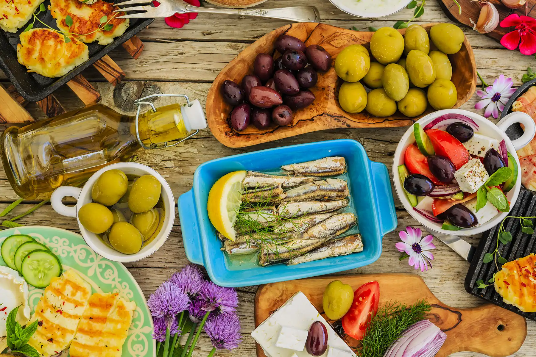 Various different food options that make up the Mediterranean diet, including olive oil, fish, fruits, vegetables, and spices.