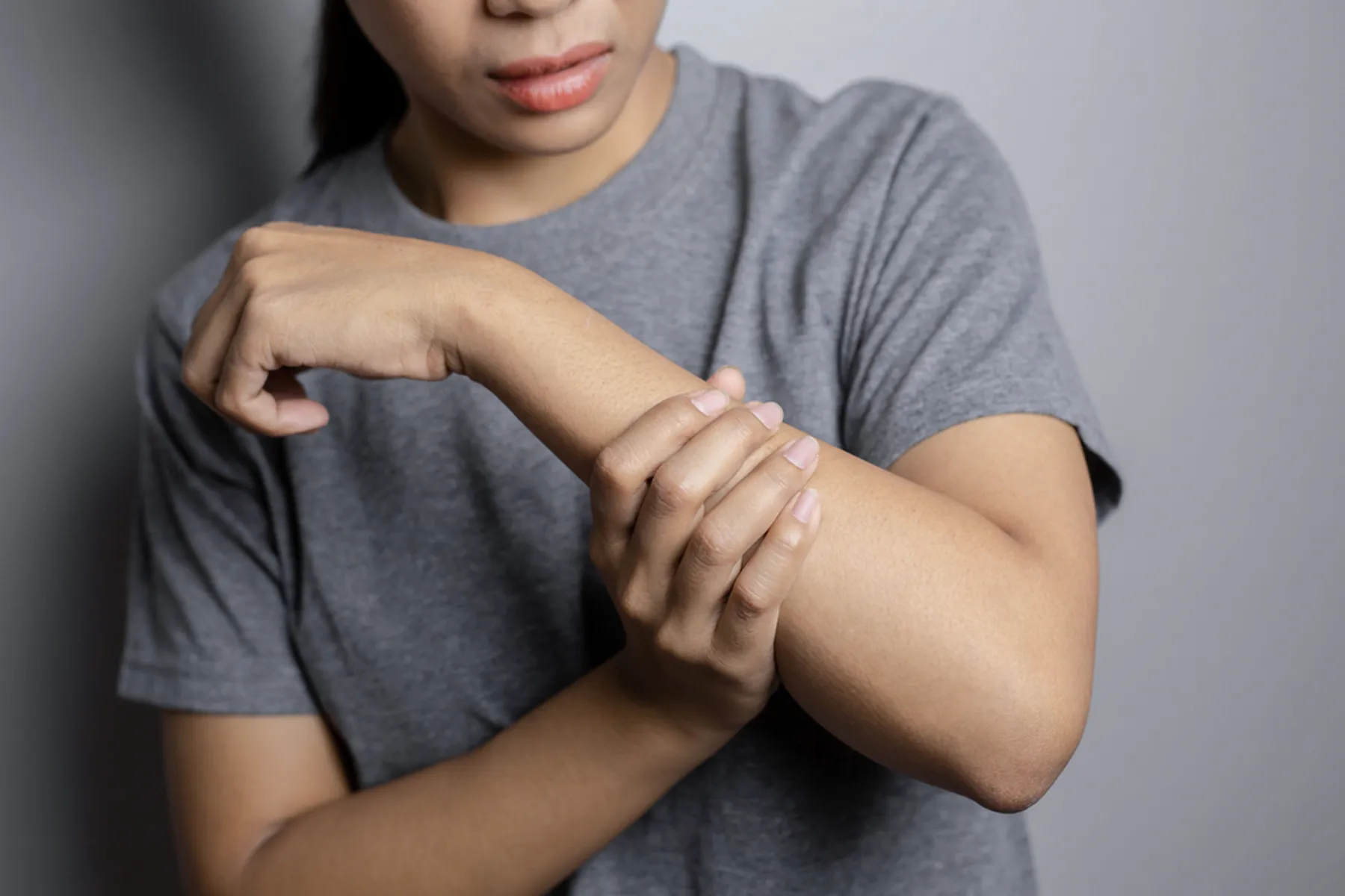 A woman holds her arm, indicating nerve pain (Neuropathy)