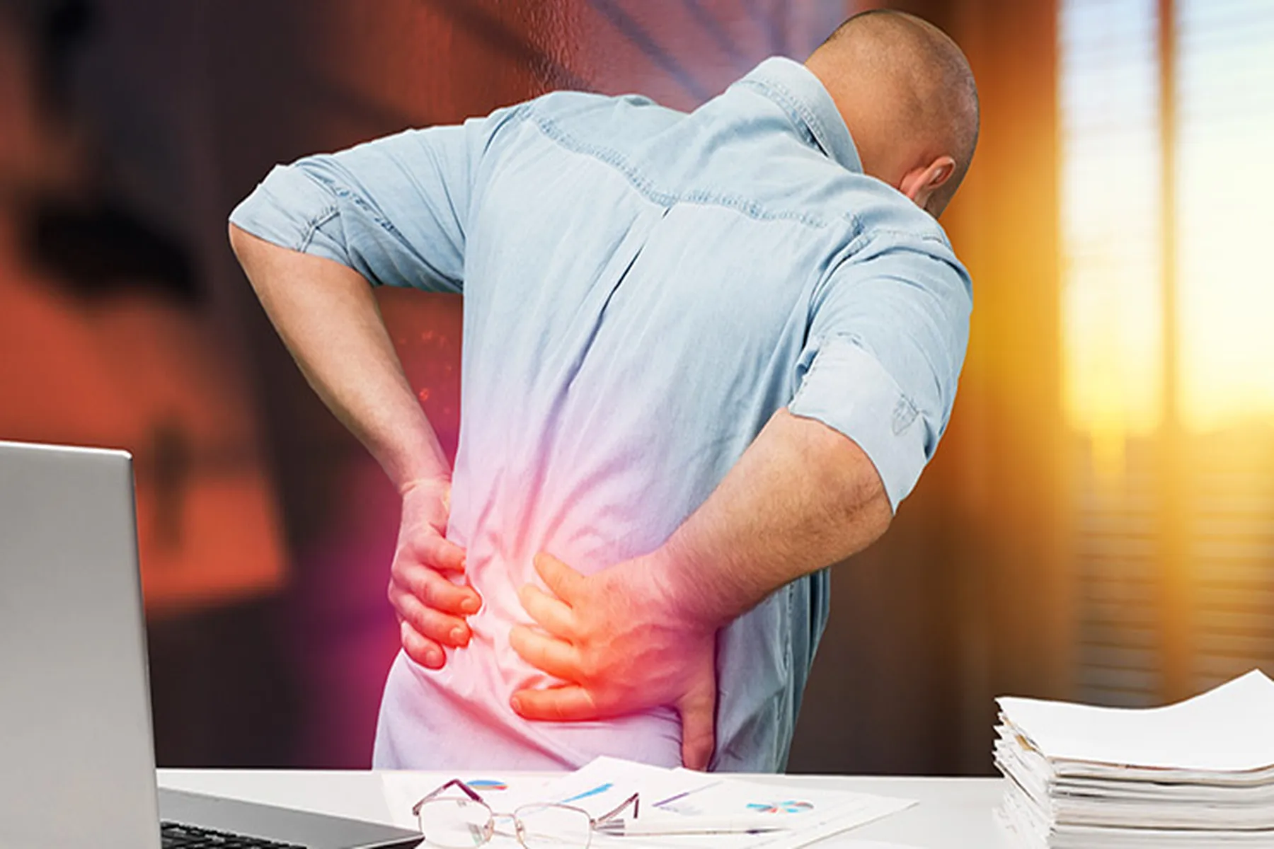 A man holds his back in pain, with a graphic of red radiating from the area.