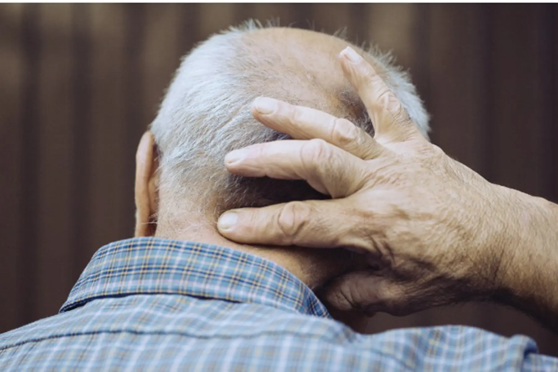 Man pressing bump on the back of his neck.