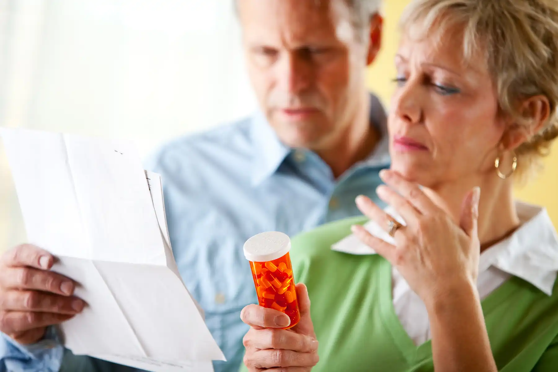 Older couple reading the label for pills.