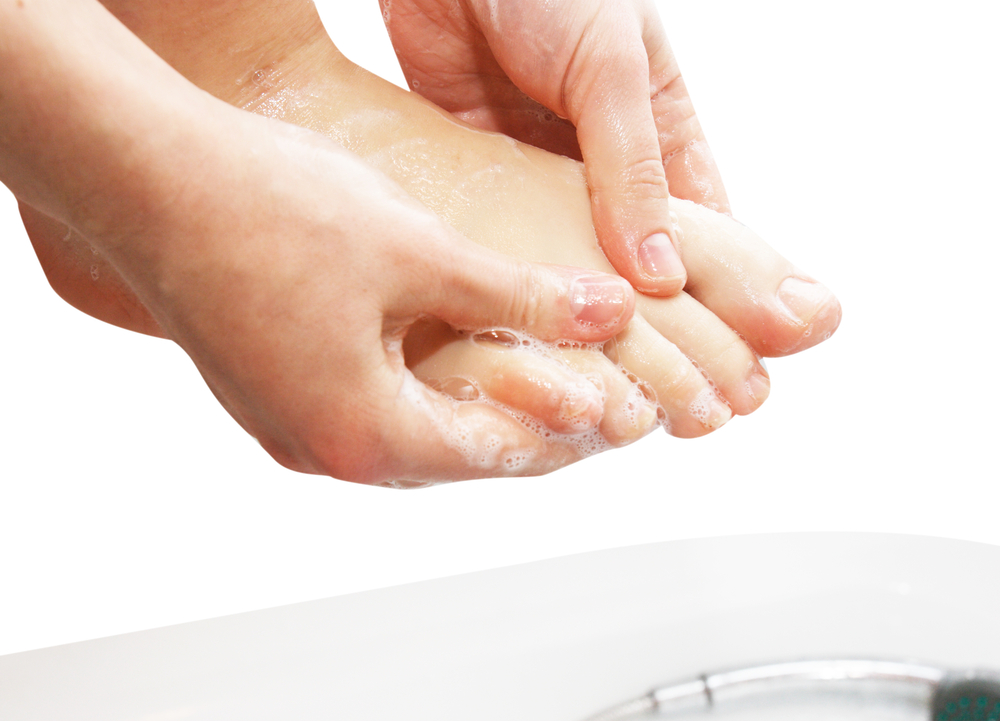 A close-up of a woman's foot as she gently washes it with some water. 