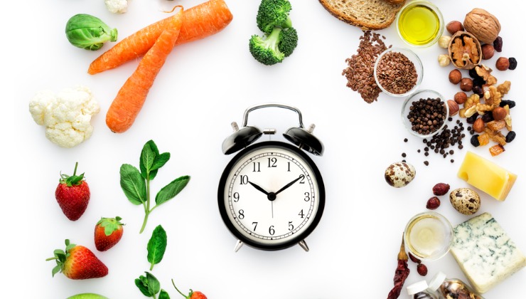 A clock surrounded by an assortment of foods.