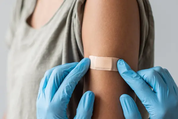 Doctor putting band-aid on patient after HPV vaccine.
