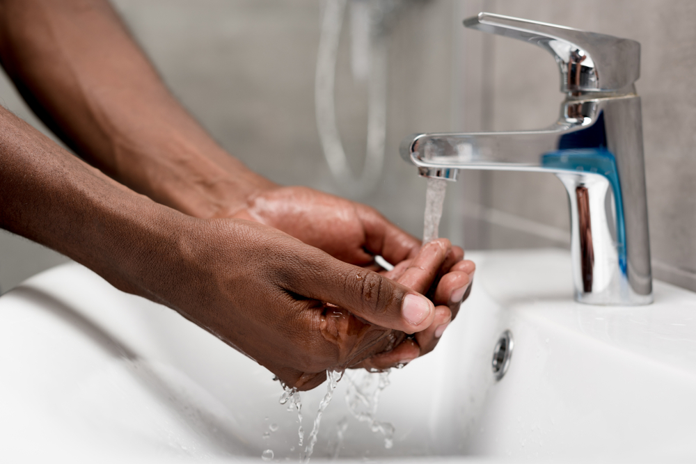 A close-up of someone's hands as they rinse them at the sink.