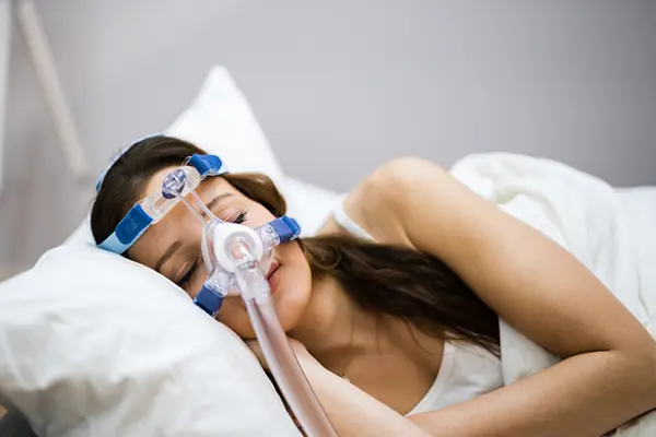 Woman sleeping on her side with CPAP machine on her face.
