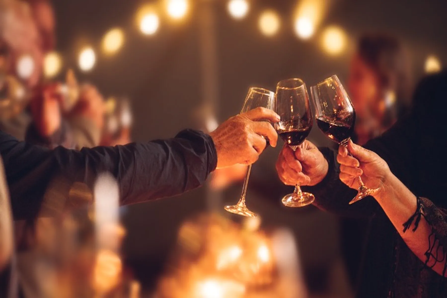 Three people cheersing with red wine.