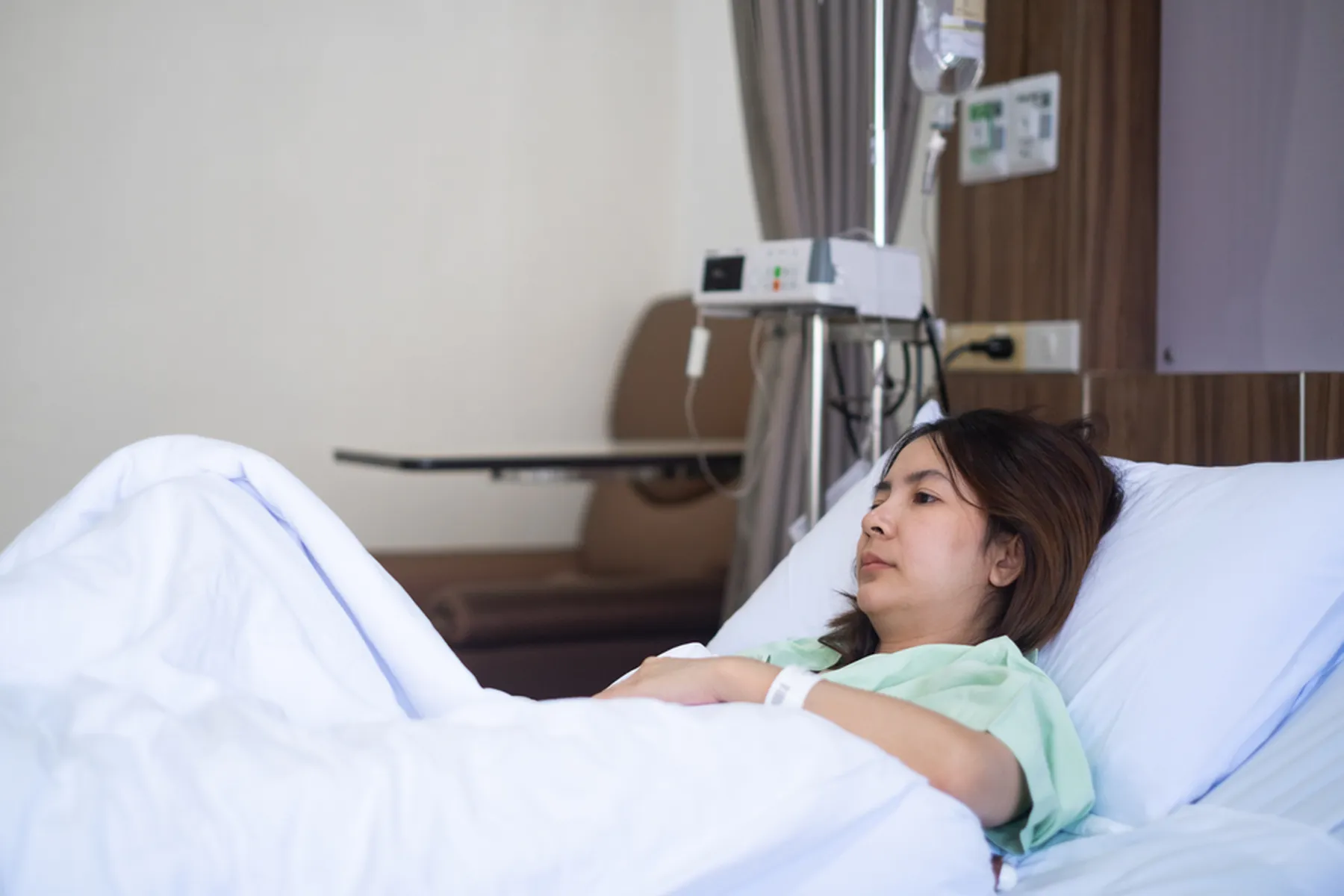 A woman in a hospital gown lays in a hospital bed.