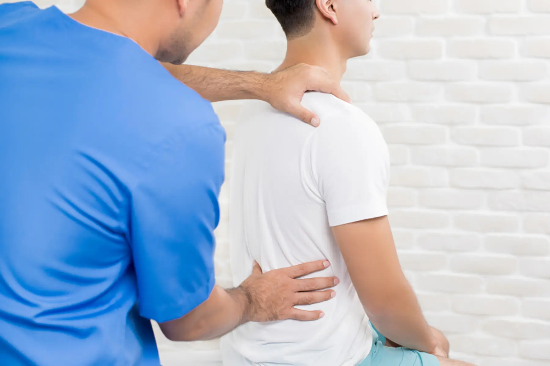 A healthcare professional assesses and/or works on the back of a client. 