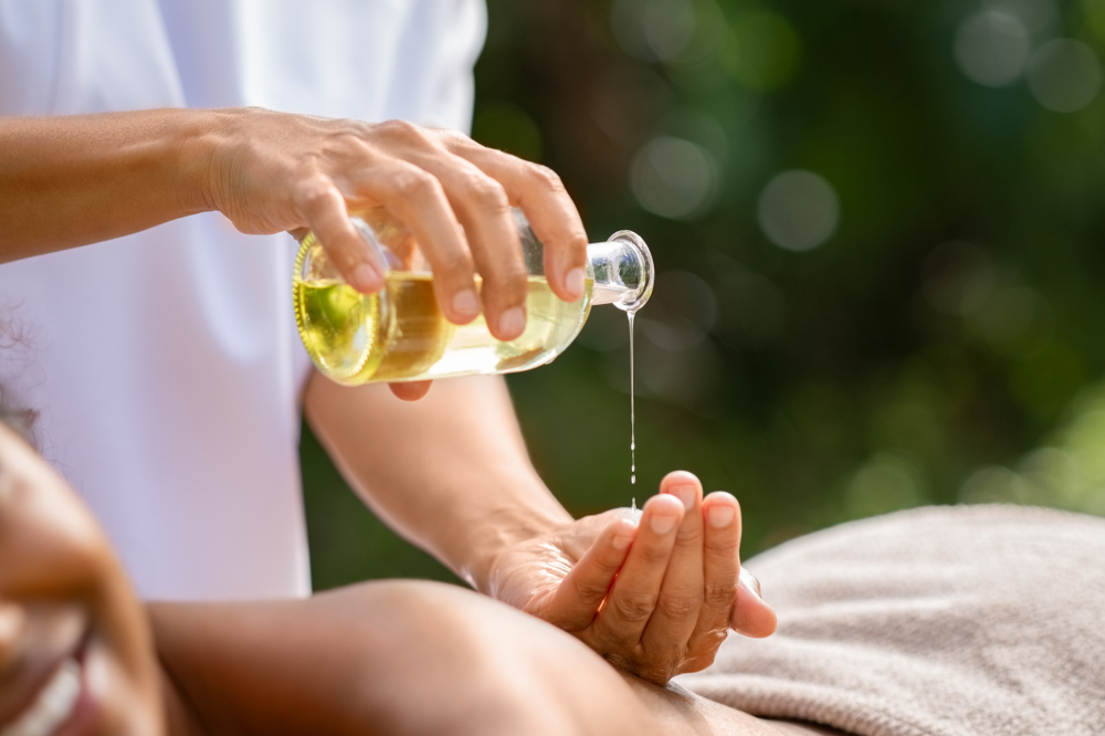 A massage therapist pours an essential oil into their hand.
