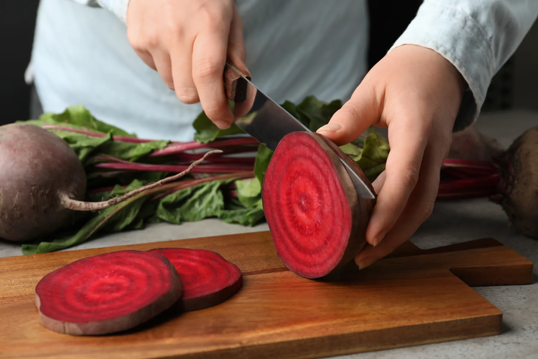 A chef slices a beet.