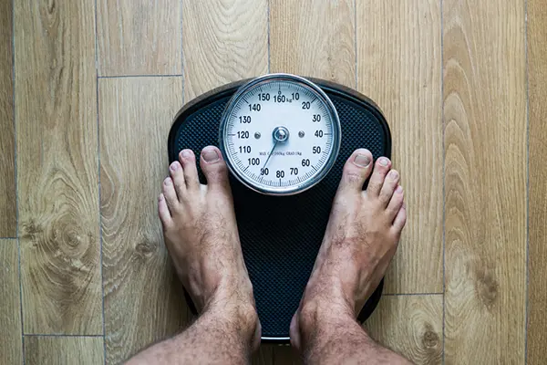 A man stands on a scale to measure his weight.