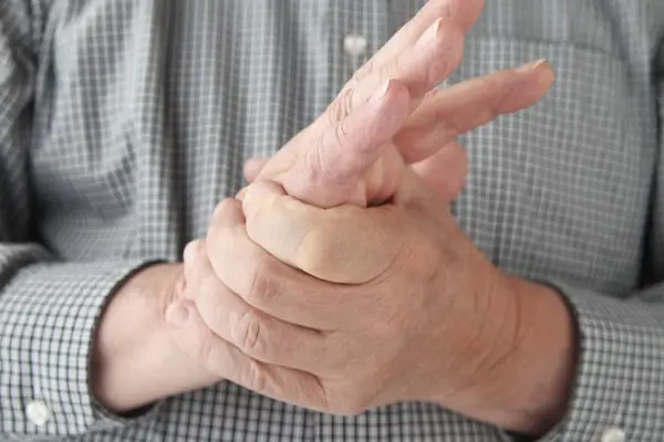 Older man squeezing his own hand.