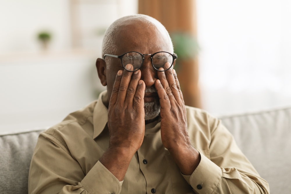 Older man rubbing his eyes.