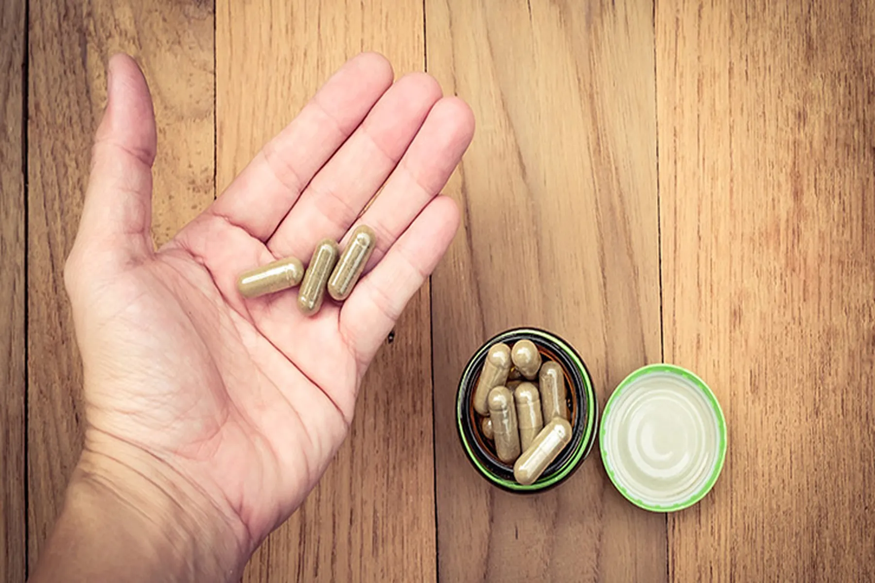 A hand holds a few pills of fiber supplements.