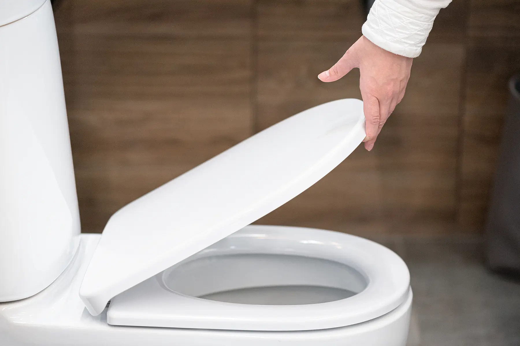 A woman holding the toilet cover