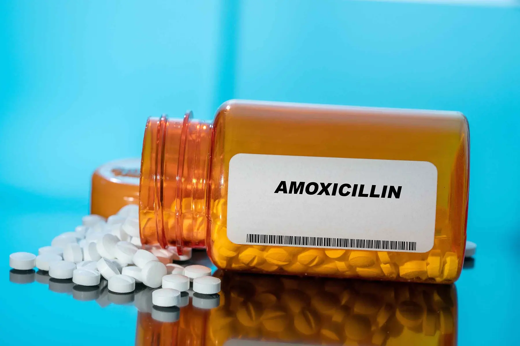 Amoxicillin pill bottle toppled over with pills spilling out.
