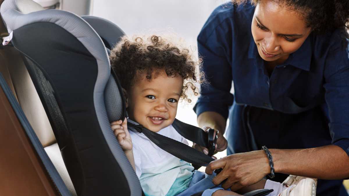 Mom buckles child into car seat