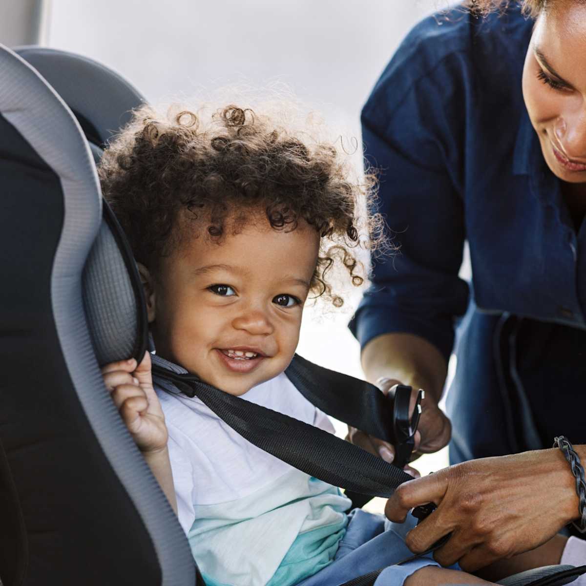 Mom buckles child into car seat Mom buckles child into car seat