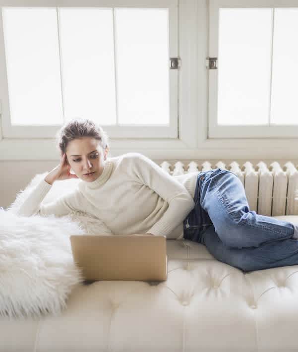 Young woman with laptop relaxing on her sofa at home office