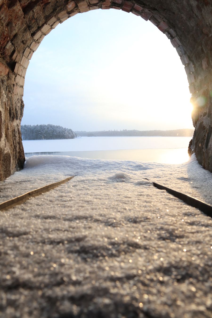 Aurinkoinen järvimaisema, jota ympäröi tiiliseinät
