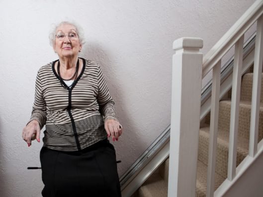 Frau vor Treppe mit Stehlift