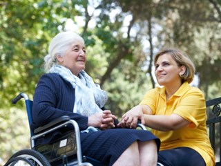 seniorin-mit-pflegerin-im-gruenen