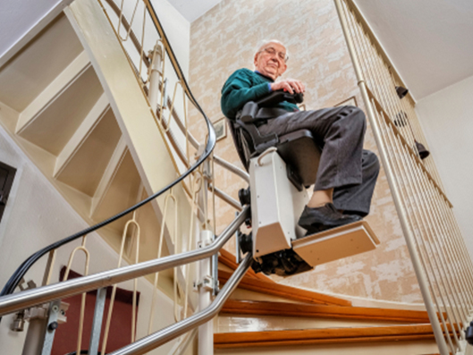 Senior fährt mit seinem eingebauten Treppenlift seine Treppe hinunter.