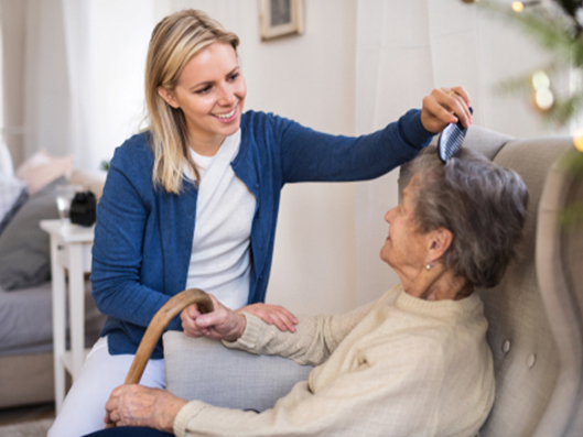 Intensivpflegekraft kümmert sich um Seniorin im eigenen Zuhause.