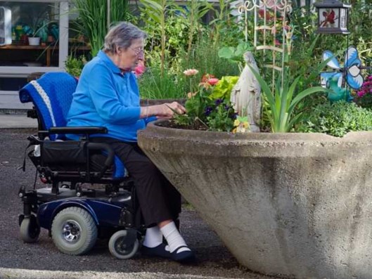 Seniorin auf einem Elektrorollstuhl im Außenbereich.