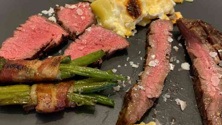 Flank Steak und Rinder Filet Steak mit Bohnen im Speckmantel und Kartoffelgratin auf dem Teller