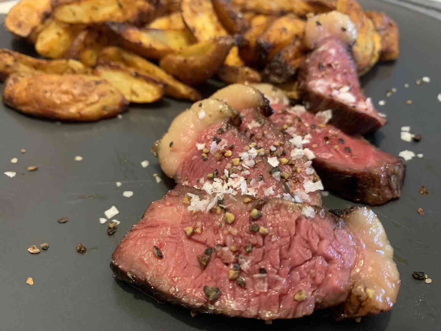 Picanha Steak mit Salz auf dem Teller. Dazu gibt es Kartoffeln