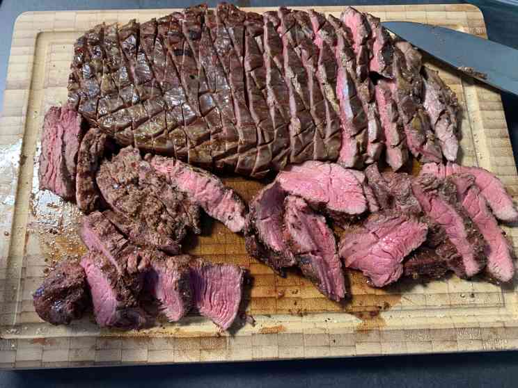 Flank Steak auf einem Holzbrett medium-rare aufgeschnitten